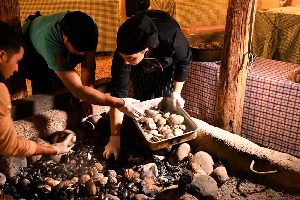 Chileans adding shellfish to the Curanto, Chiloe Island